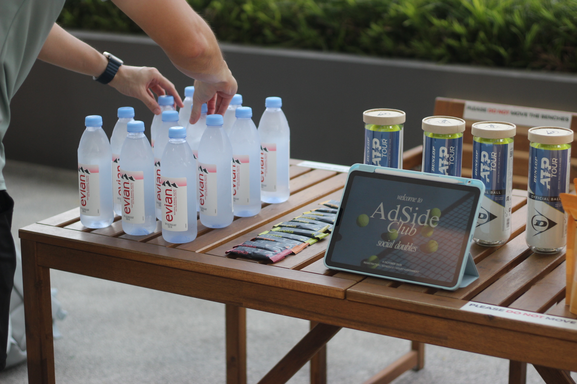 Preparing the AdSide Club social doubles welcome table with drinks, tennis balls and a welcome screen